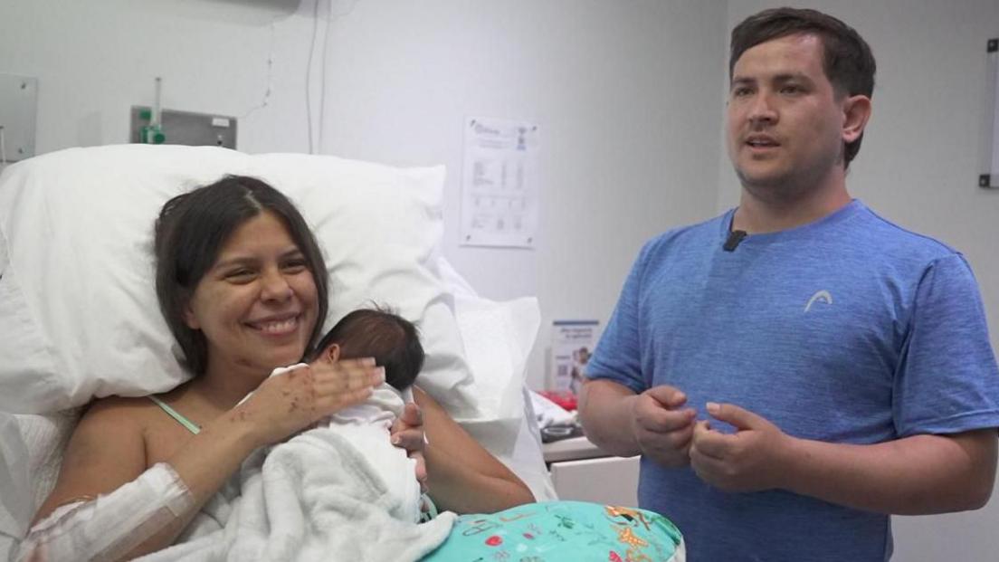 Mother Dayana Patino holds her newborn son in a hospital setting after rescue