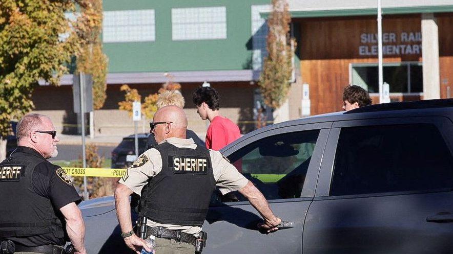Two men in bullet proof vests on a school building