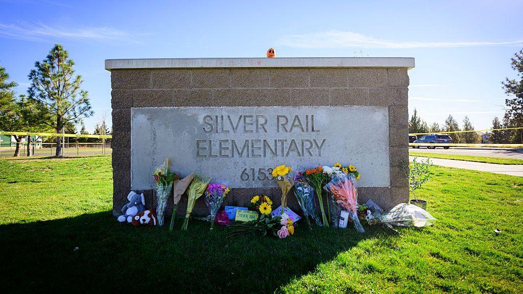Flowers lay against the entrance sign of Silver Rail Elementary School